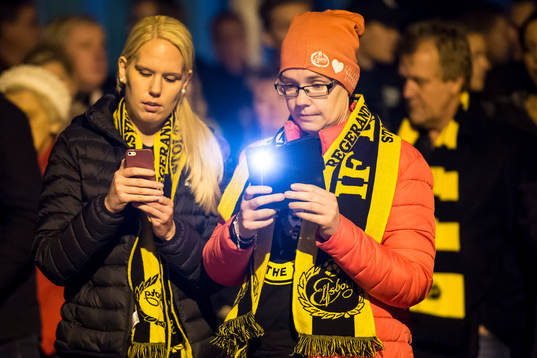 Sörjande supportrar fotograferar med mobiltelefoner