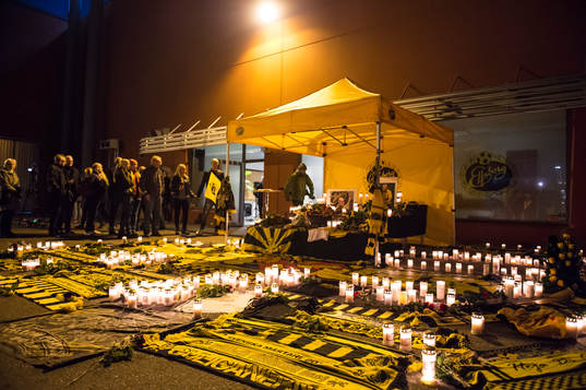 Supportar har satt ljus och lagt ner halsdukar och blommor