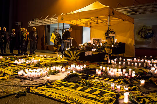 Supportar har satt ljus och lagt ner halsdukar och blommor