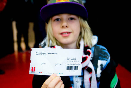 En ung supporter håller upp matchbiljetten