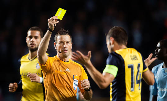 domare Mark Clattenburg ger gult kort till Atletico Madrids