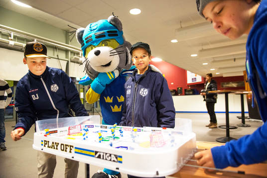 Ungdomar spelar bordshockeyspel i entrén till Tegera Arena