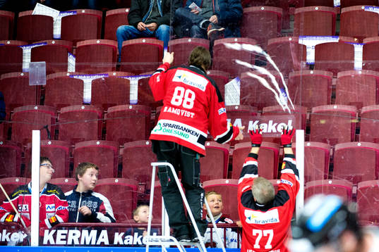 Två funktionärer rättar till ett plexiglas som hamnat