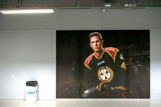 Spelarporträtt på Brynäs Greg Scott före på en vägg