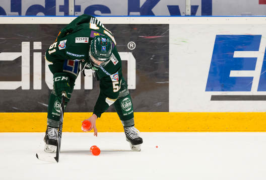 Färjestads Rickard Wallin plockar upp flaskor från isen