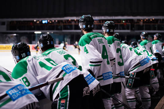 Rögles spelare hänger ut över sargen och följer spelet