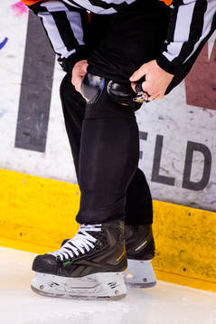 En domare rätar till sitt knäskydd före ishockeymatchen