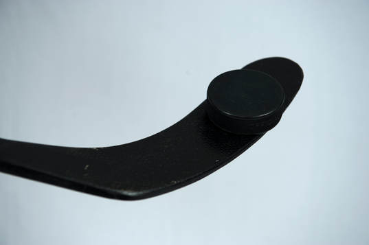 En ishockeypuck på en ishockeyklubba