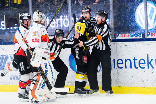 Domare Johan Häll (th) med linjedomare försöker stoppa