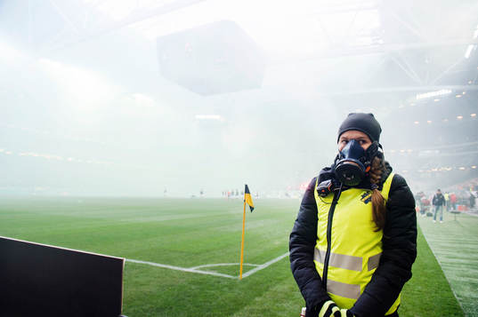 En publikvärd har en gasmask på sig