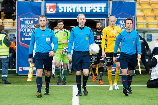 Domare och spelare på inmarsch innan fotbollsmatchen i