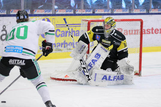 Rögles Calle Rosén med puck mot Västerås målvakt Jonas