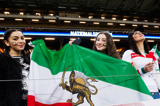 Supportrar håller upp en Iransk flagga med ett lejon på