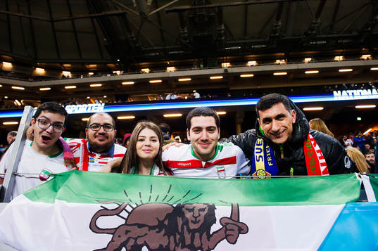 Supportrar håller upp en Iransk flagga med ett lejon på