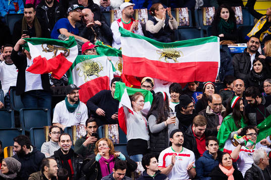 Supportrar håller upp Iranska flaggor med lejon på
