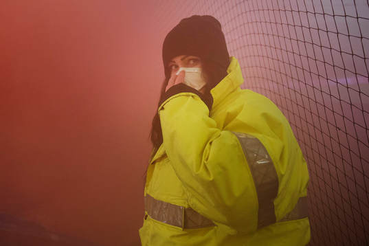 En publikvärd med mask för att komma undan röken