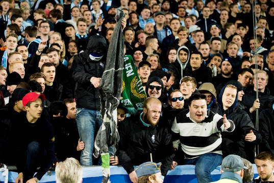 En maskerad malmösupporter bränner en Hammarbys flagga