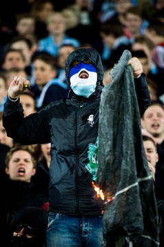En maskerad malmösupporter bränner Hammarbys flagga