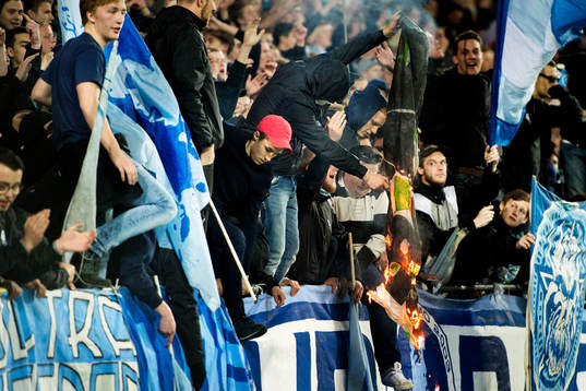 En maskerad malmösupporter bränner en Hammarbys flagga