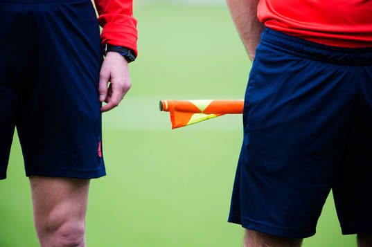 En linjedomare håller i en ihoprullad offsideflagga