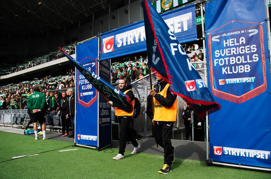Ungdomar med fanor gör entré till fotbollsmatchen i