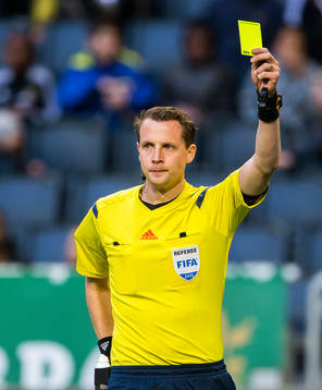 Domare Andreas Ekberg håller upp det gula kortet
