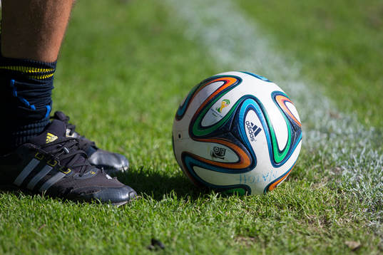 En fotboll ligger framför en spelares fötter