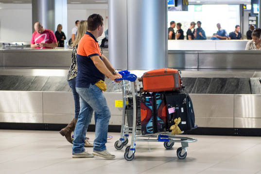 En man och en kvinna kör en bagagevagn på en flygplats