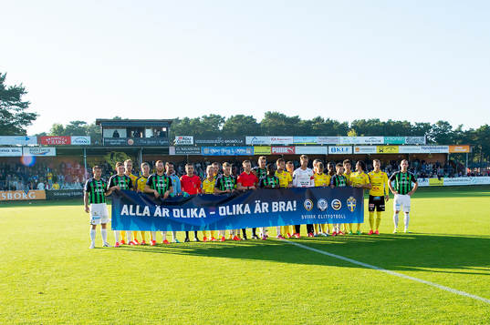 Spelarna håller upp en banderoll innan fotbollsmatchen i
