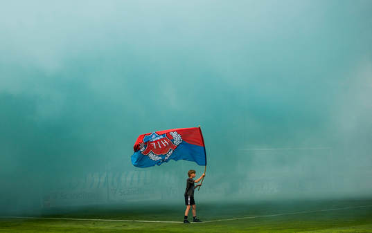 En ung pojke vevar en Helsingborg flagga i tung rök
