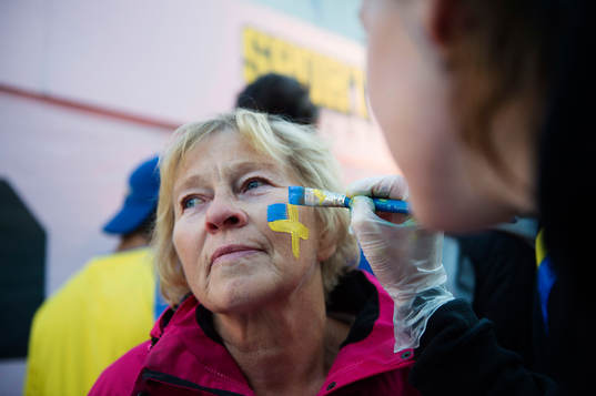 En kvinna får en ansiktstmålning i fanzon