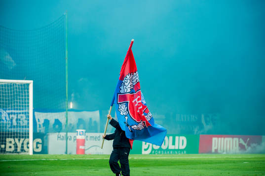En funktionär bär en Helsingborgsflagga framför IFK