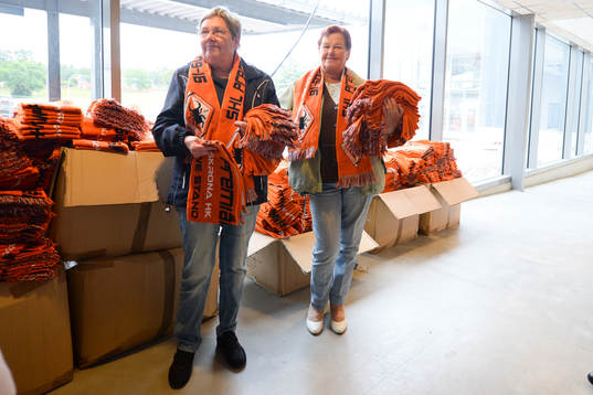 två funktionärer delar ut halsdukar innan ishockeymatchen
