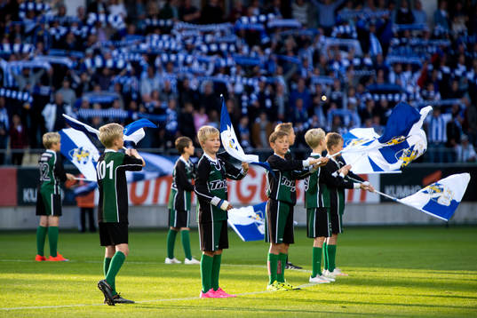 Knattar vevar med flaggor innan en fotbollsmatch i