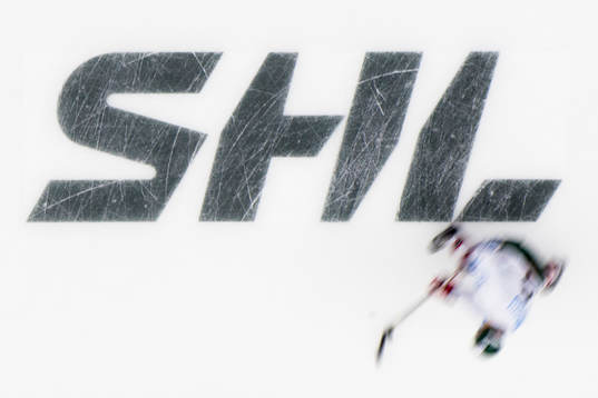 Spelare värmer upp på isen över SHL logotype
