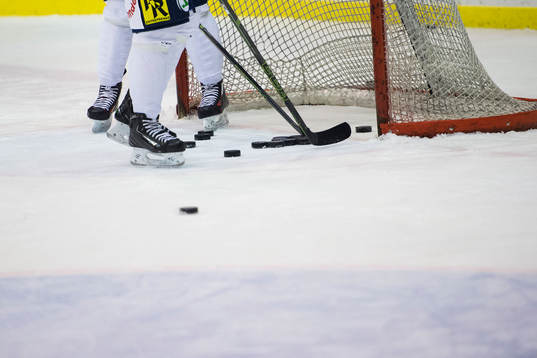 Två spelare plockar ut puckar ur ett mål