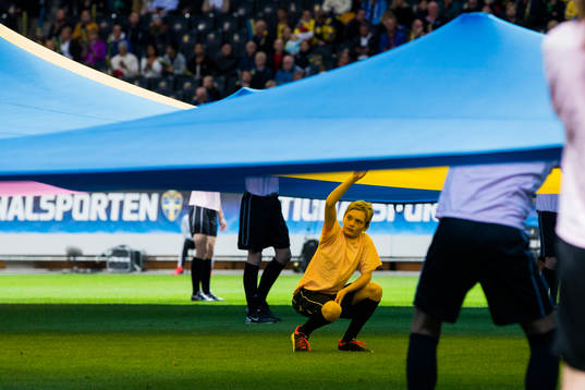 En ungdom hjälper till att hålla upp en stor svensk