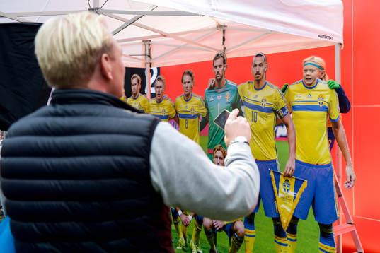 En pappa tar en bild av sin son vid en fotvägg i  Fan Zone