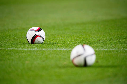 Två fotbollar på naturgräset