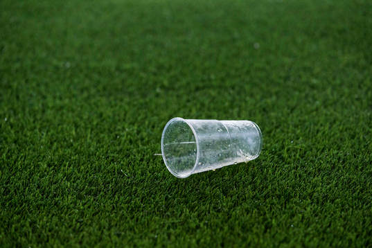 Ett tomt engångsglas ligger på planen
