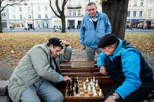 Två äldre herrar spelar schack på en parkbänk en