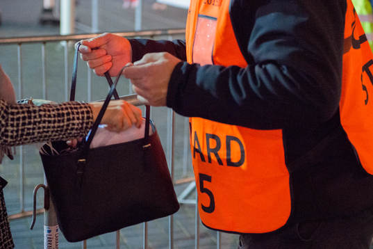 En publikvärd söker igenom en väska vid insläppet till