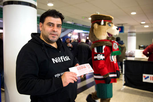 En man säljer 50/50-lotter innan ishockeymatchen i SHL
