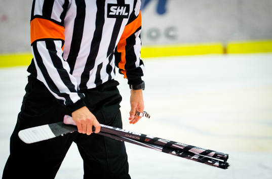 En SHL domare med en avbruten ishockeyklubba i handen
