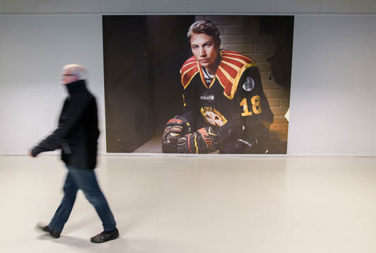 En man går förbi ett spelarporträtt utav Brynäs Anton