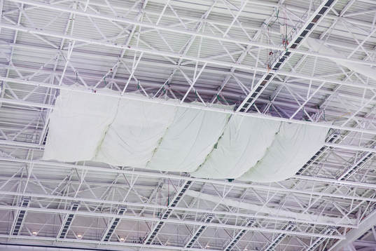 Presenningar hänger i taket på Tele2 Arena för att