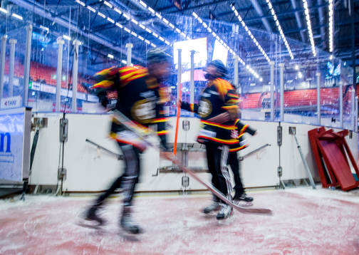 Ungdomar åker skridskor på en isfläck intill sargen