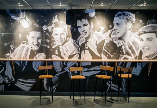 Fotovägg utav forna Brynässpelare på en barvägg inne