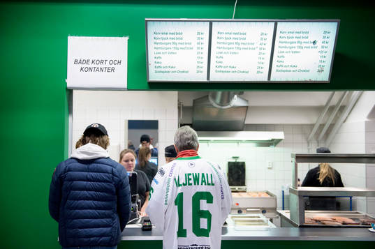 Två åskådare köar till kiosken