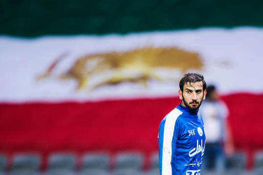 Esteghlals Amin Hajmohammadi framför en stor Iransk flagga